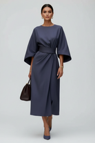 Woman in a dark blue dress walking on a city street.