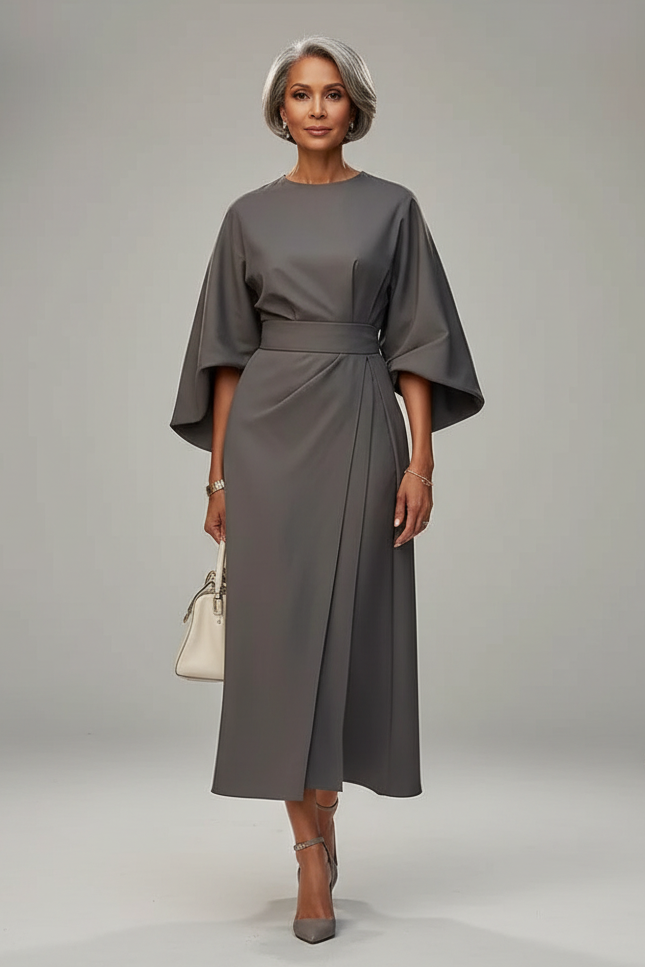 Woman in a gray dress walking on a city street.