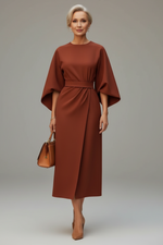 Woman wearing a brown dress with cape sleeves on a city street.
