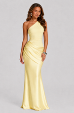 Woman wearing a yellow one-shoulder gown on a gray background