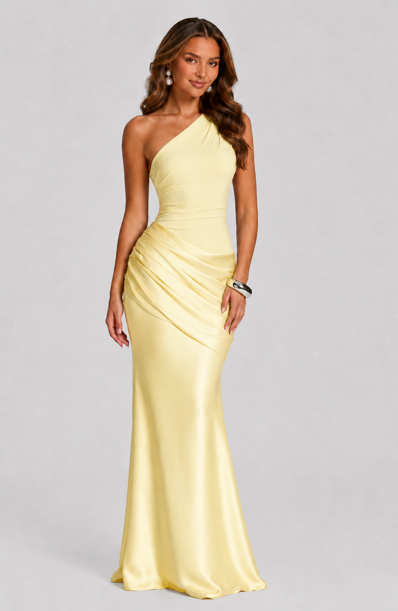 Woman wearing a yellow one-shoulder gown on a gray background