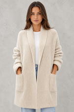 Woman wearing a beige cardigan against a gray background