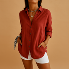 Person wearing a red button-up shirt and white shorts on a brown background