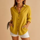 Woman wearing a mustard yellow shirt and white shorts on a beige background