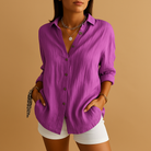 Person wearing a purple button-up shirt and white shorts on a brown background