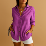 Person wearing a purple button-up shirt and white shorts on a brown background