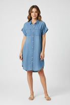 Woman wearing a blue denim dress against a neutral background