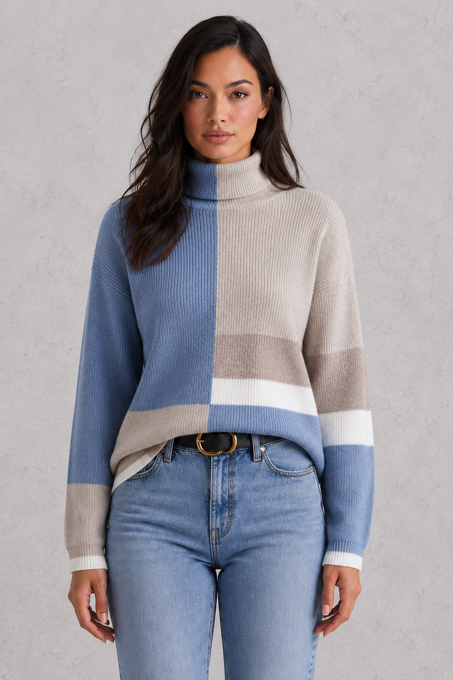 Woman wearing a color-blocked sweater and jeans against a gray background