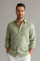 Man wearing a light green shirt and white pants in a modern living room.