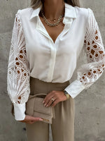 White blouse with lace sleeves worn by a person against a gray concrete wall.