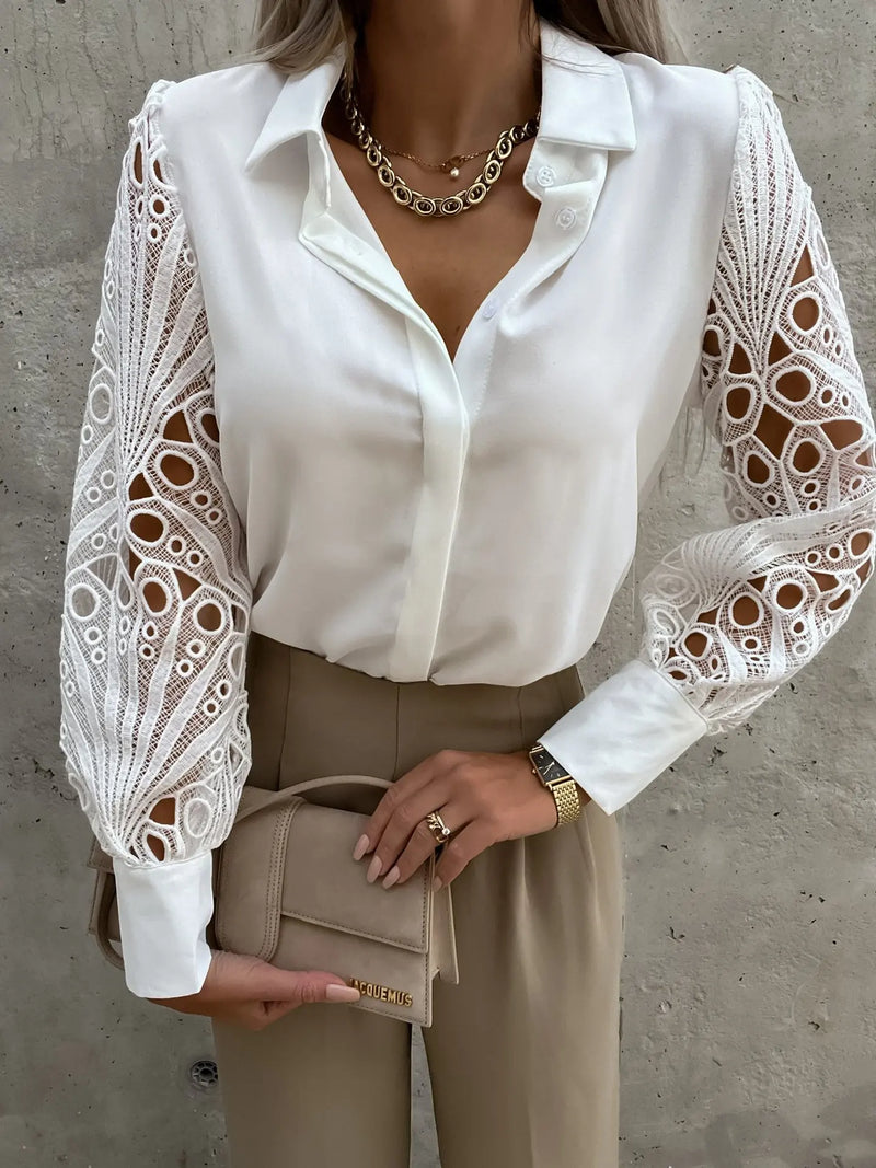 White blouse with lace sleeves worn by a person against a gray concrete wall.