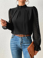 Person wearing a black blouse with long sleeves and blue jeans against a white background