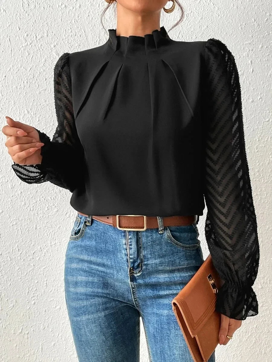 Person wearing a black blouse with long sleeves and blue jeans against a white background
