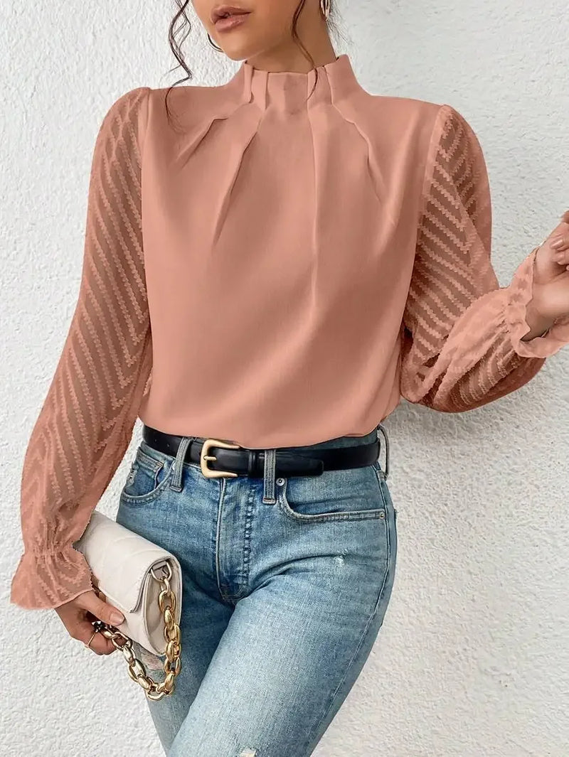 Person wearing a pink blouse with sheer sleeves and blue jeans against a white background