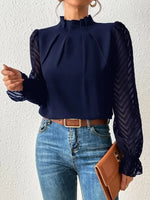 Person wearing a navy blue blouse with long sleeves and blue jeans against a white background