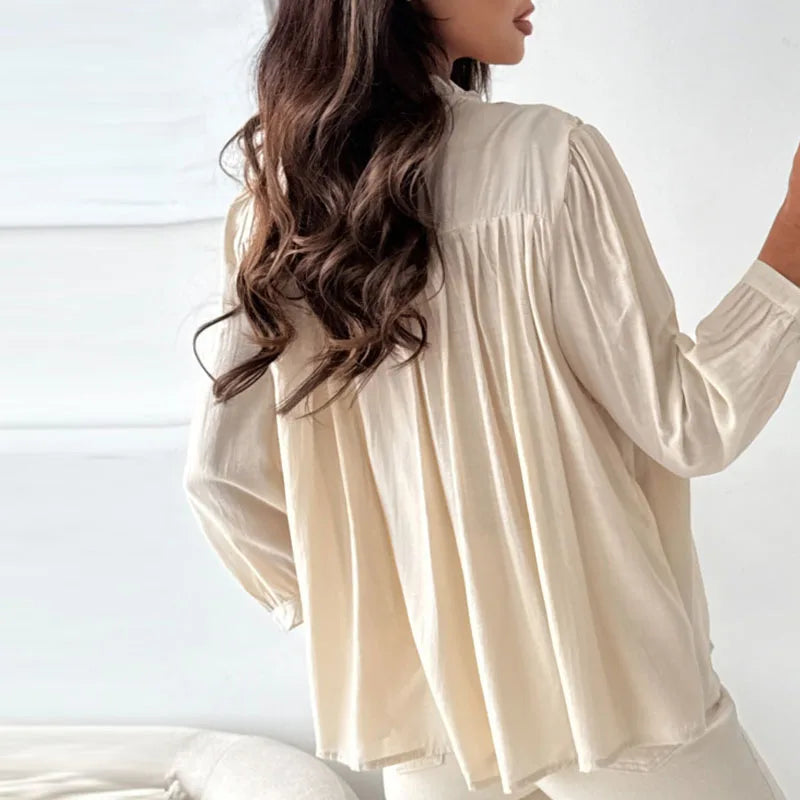Woman wearing a beige blouse with long sleeves against a white background