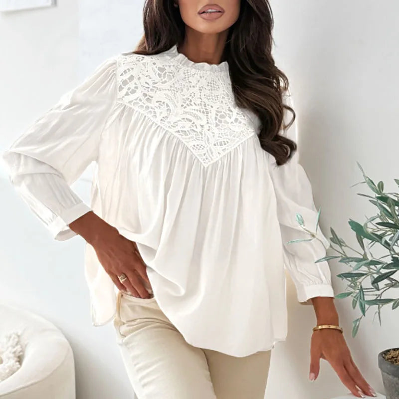 Woman wearing a white blouse with lace details in a minimal indoor setting.