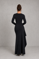 Woman wearing a black evening gown against a gray background