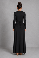 Person wearing a black long-sleeve dress against a gray background