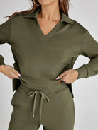 Person wearing an olive green outfit with a matching jacket and pants on a plain background