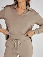 Person wearing a beige long-sleeve top and pants set on a plain background