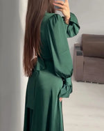 Person wearing a green dress standing in a room with a sofa.