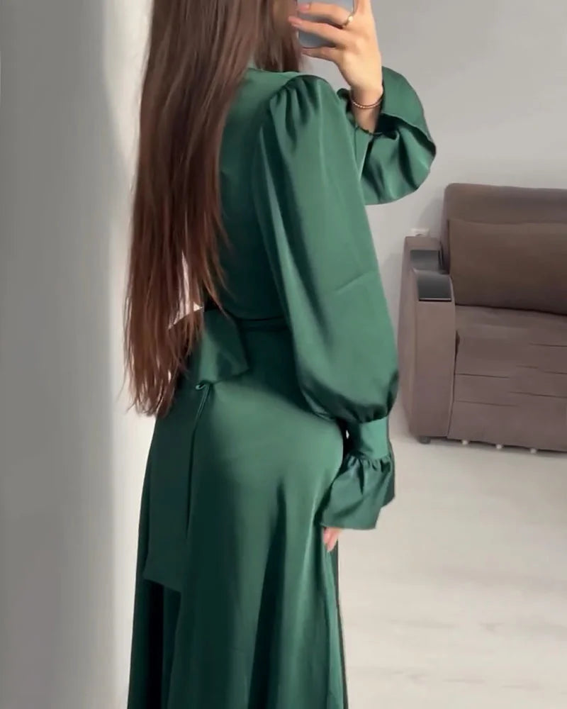 Person wearing a green dress standing in a room with a sofa.