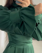Person wearing a green dress with puffed sleeves in front of a mirror.