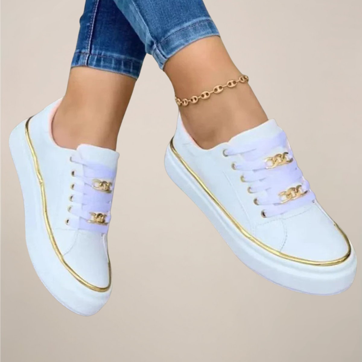 White sneakers with gold accents worn by a person on a beige background