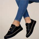 Black platform sneakers worn with blue jeans on a beige background