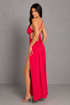 Woman wearing a red dress with an open back and high slit on a gray background