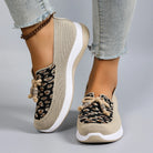 Beige sneakers with black pattern worn by a person on a gray background