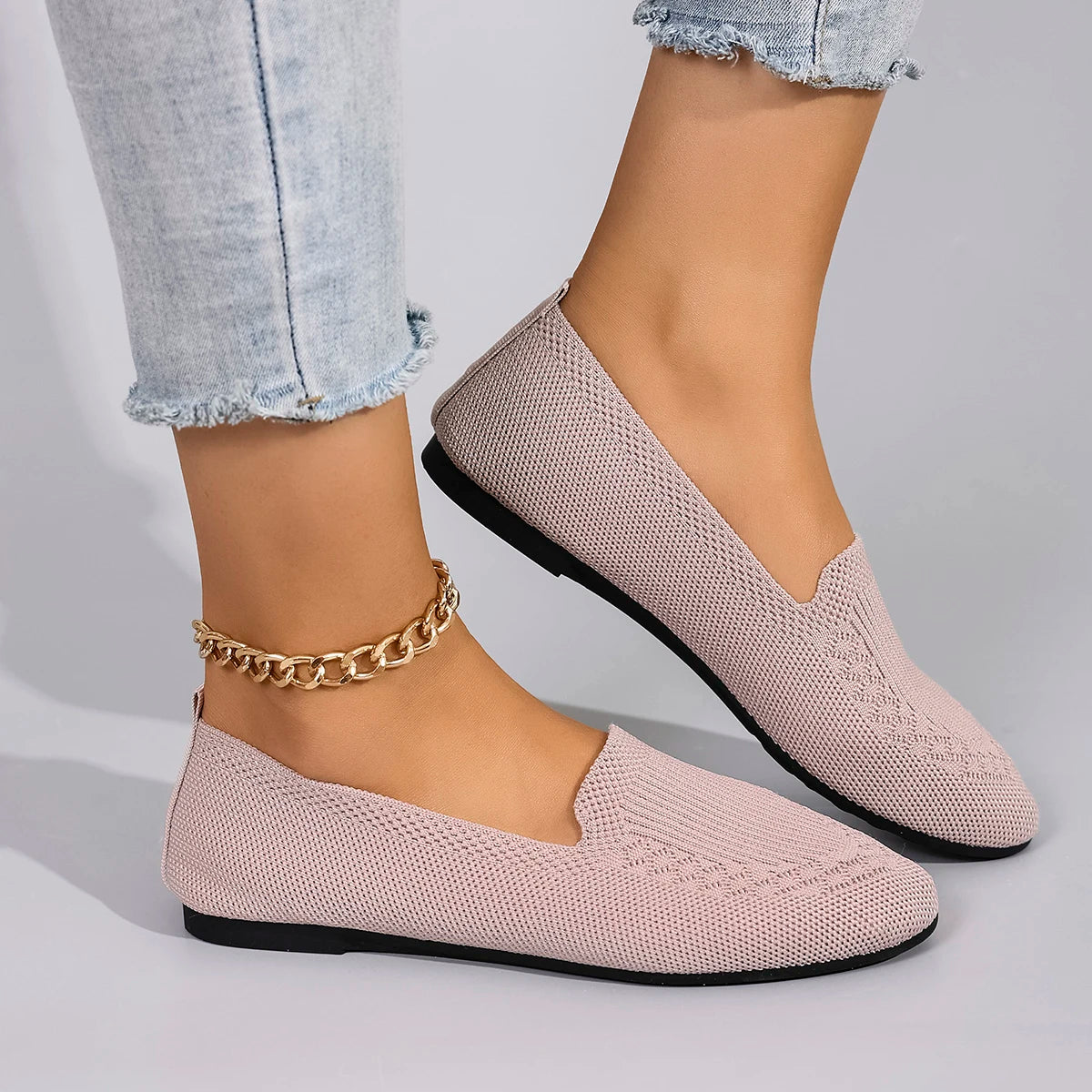 Pink loafers worn with light blue jeans on a neutral background