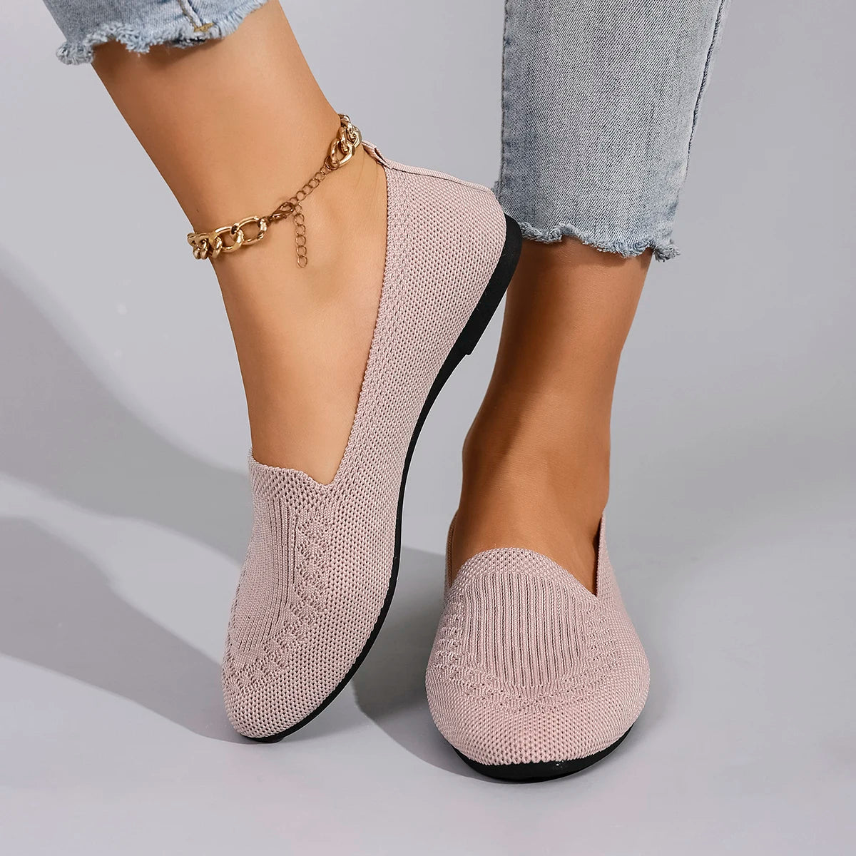 Beige knitted loafers worn with light blue jeans on a gray background