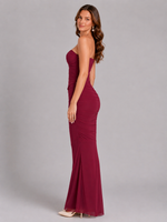 Woman wearing a burgundy strapless gown with open back on a gray background