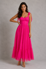 Woman wearing a bright pink dress against a gray background