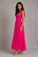 Woman wearing a bright pink one-shoulder dress against a gray background