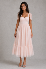 Woman wearing a light pink dress against a gray background