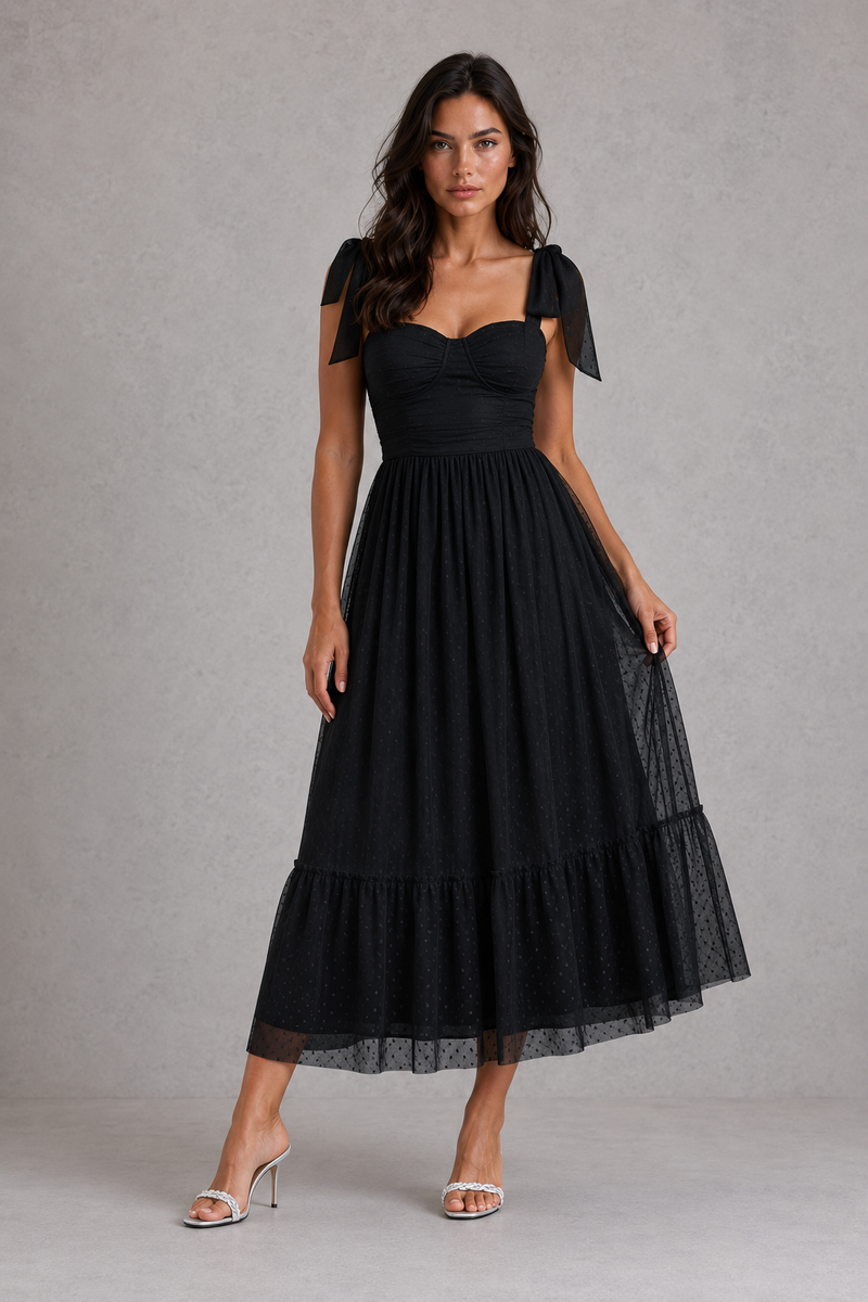 Woman wearing a black dress with bow sleeves against a gray background