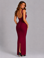 Woman wearing a burgundy evening gown with a high slit on a gray background