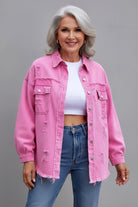 Person wearing a pink distressed denim jacket over a white top and blue jeans on a gray background