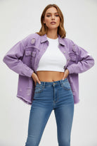 Woman wearing a light purple denim jacket, white top, and blue jeans against a gray background