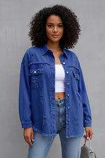 Woman wearing a blue denim jacket and jeans against a gray background