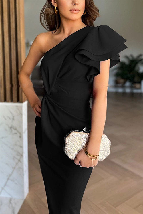 Woman wearing a black one-shoulder dress holding a white clutch with pearl details.