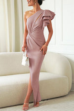 Woman wearing a one-shoulder pink dress in a room with a beige sofa.
