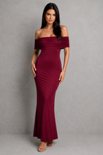 Woman wearing a burgundy off-shoulder gown against a gray background