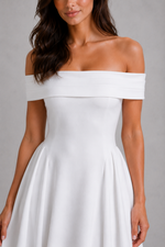 Woman wearing a white off-shoulder dress against a gray background