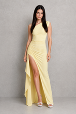 Woman wearing a yellow one-shoulder dress with a slit on a gray background