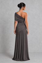 Woman wearing a gray one-shoulder dress against a plain background