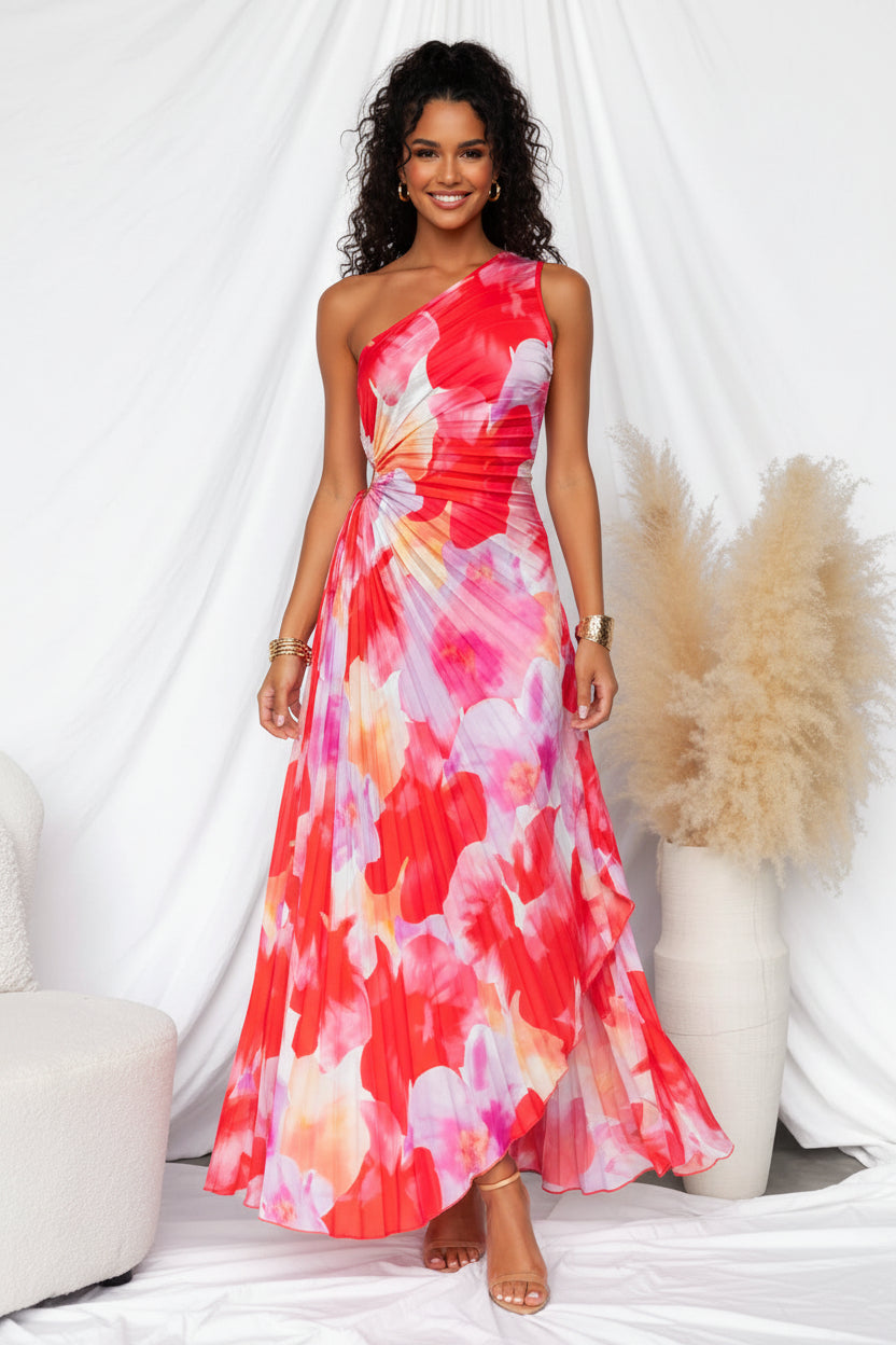 Woman wearing a colorful one-shoulder dress in a minimal indoor setting.